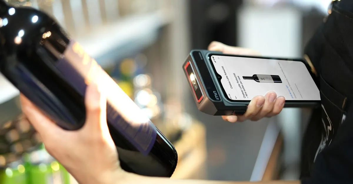 A handheld barcode scanner reading a striped barcode on a cardboard shipping package