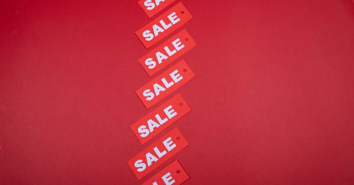 Red sale price tags hanging on a rail in a clothing store during a discount sale