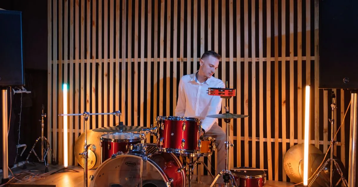 Drummer practising on a drum kit in a studio, keeping time with a metronome click